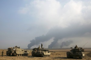 Israeli soldiers stand atop tanks outside northern Gaza Strip