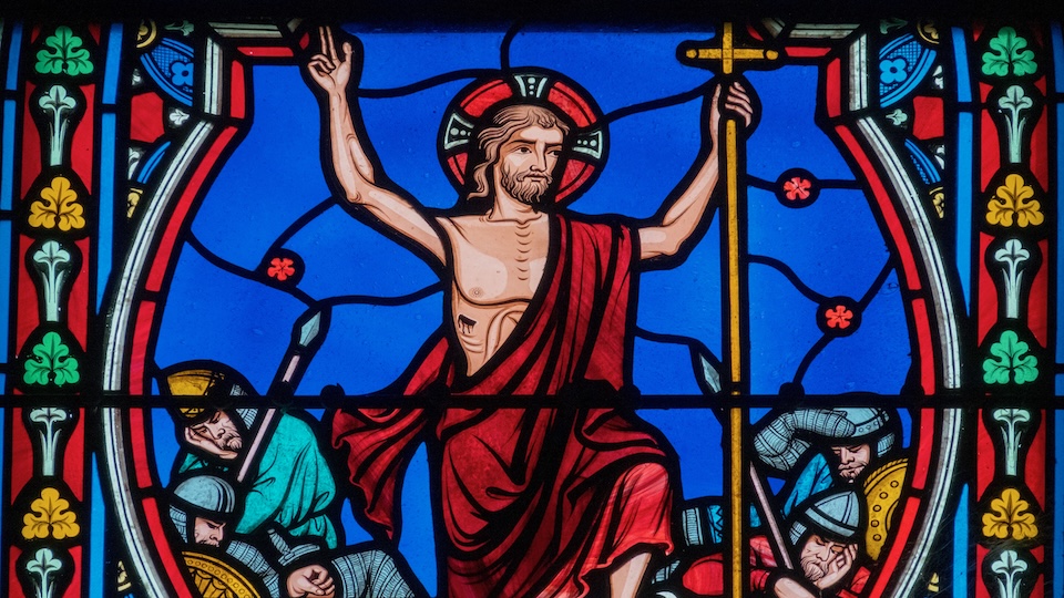 Vitrail de Jésus ressuscité devant un fond bleu.